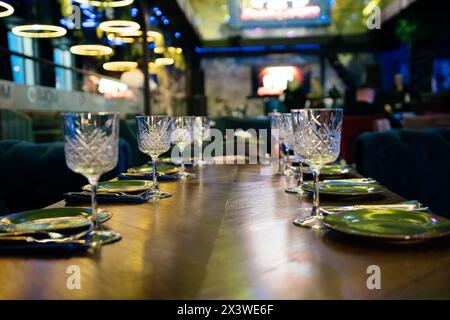 Une table avec un certain nombre de verres à vin et assiettes. La table est dressée pour un repas. Scene est élégant et sophistiqué. Banque D'Images