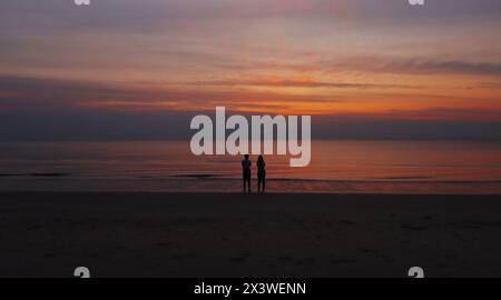 Silhouette du couple debout à la plage regardant lever de soleil à la plage de Thaïlande Banque D'Images