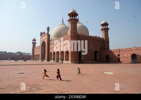 Pakistan, Lahore, les enfants jouent dans la cour intérieure de la grande mosquée Badshahi, architecture Moghol du 17ème siècle, le sist jumeau Banque D'Images