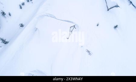 Cabanes en bois dans la neige profonde sur la vallée de montagne en hiver, vue de dessus. Chalets enneigés pour touristes en montagne hivernale Banque D'Images