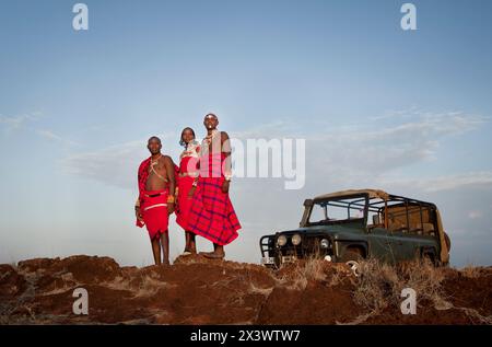 Trois guides safari Massaï se tiennent près d'un landrover pour un portrait au coucher du soleil. Les guides travaillent avec le Lodge Sirikoi à Lewa Downs, au Kenya. Banque D'Images