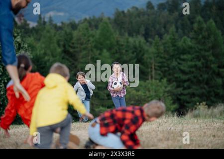 Jeunes élèves jouant avec le professeur à l'extérieur, dans la nature, pendant la classe d'enseignement sur le terrain, s'amusant. Enseignants dévoués pendant l'éducation active en plein air. Banque D'Images