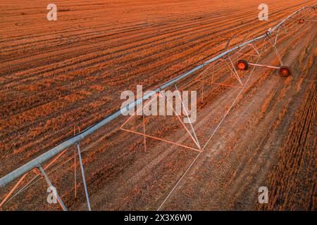 Ligne d'irrigation agricole avec déplacement latéral dans un champ de colza récolté, prise de vue aérienne depuis un drone pov, vue en angle élevé Banque D'Images