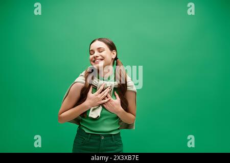 Une jeune femme dans la vingtaine rayonne de joie, tenant ses mains ensemble dans un geste de bonheur. Banque D'Images