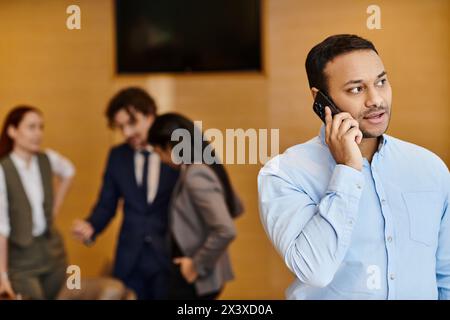 Un homme se tient devant un groupe interracial, parlant au téléphone portable. Banque D'Images