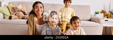 Une jeune mère asiatique et ses petits fils sont confortablement assis ensemble sur un canapé dans le salon de leur maison. Banque D'Images