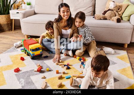 Une jeune mère asiatique et ses petits fils construisent joyeusement des structures avec des blocs colorés sur le sol de leur salon. Banque D'Images