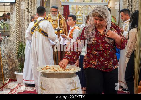 Bartella, Irak. 28 avril 2024. Un adorateur chrétien prend la sainte communion pendant le service du dimanche des Rameaux, marquant le début de la semaine Sainte pour les chrétiens orthodoxes, à l'église orthodoxe syriaque de Mart Shmoni. (Photo de Ismael Adnan/SOPA images/SIPA USA) crédit : SIPA USA/Alamy Live News Banque D'Images