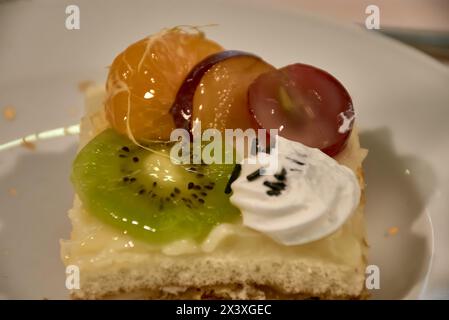 Tartes aux fruits frais mélangés prêtes pour le dessert dans l'assiette. Délicieux gâteau sucré avec kiwi, raisin, orange et aussi crème. Mise au point sélective. fermé Banque D'Images