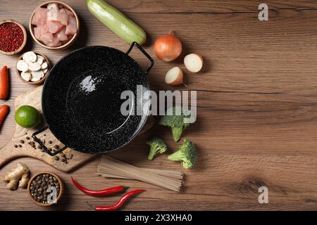 Wok en fer vide entouré d'ingrédients bruts sur une table en bois, plat Banque D'Images