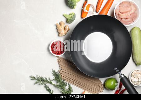 Wok en fer vide entouré d'ingrédients crus sur table lumineuse, plat. Espace pour le texte Banque D'Images