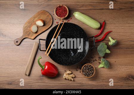 Wok en fer vide entouré d'ingrédients bruts sur une table en bois, plat Banque D'Images