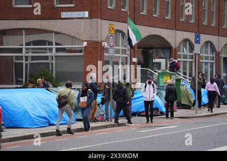 Des gens passant devant des tentes abritant des demandeurs d'asile près du Bureau de la protection internationale, à Dublin. Les allégations selon lesquelles la majorité des demandeurs d'asile entrant en Irlande avaient franchi la frontière depuis l'Irlande du Nord ont été interrogées par des organisations de défense des droits de l'homme et de réfugiés. La ministre irlandaise de la Justice Helen McEntee a affirmé la semaine dernière que le nombre de demandeurs d'asile traversant l'Irlande du Nord pour entrer dans l'État est maintenant "supérieur à 80%" suite à un changement dans les schémas migratoires ces derniers mois. Date de la photo : lundi 29 avril 2024. Banque D'Images