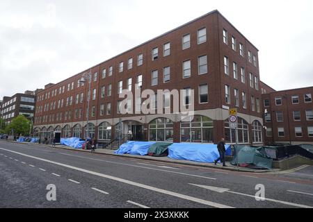 Des gens passant devant des tentes abritant des demandeurs d'asile près du Bureau de la protection internationale, à Dublin. Les allégations selon lesquelles la majorité des demandeurs d'asile entrant en Irlande avaient franchi la frontière depuis l'Irlande du Nord ont été interrogées par des organisations de défense des droits de l'homme et de réfugiés. La ministre irlandaise de la Justice Helen McEntee a affirmé la semaine dernière que le nombre de demandeurs d'asile traversant l'Irlande du Nord pour entrer dans l'État est maintenant "supérieur à 80%" suite à un changement dans les schémas migratoires ces derniers mois. Date de la photo : lundi 29 avril 2024. Banque D'Images