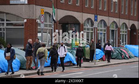 Des gens passant devant des tentes abritant des demandeurs d'asile près du Bureau de la protection internationale, à Dublin. Les allégations selon lesquelles la majorité des demandeurs d'asile entrant en Irlande avaient franchi la frontière depuis l'Irlande du Nord ont été interrogées par des organisations de défense des droits de l'homme et de réfugiés. La ministre irlandaise de la Justice Helen McEntee a affirmé la semaine dernière que le nombre de demandeurs d'asile traversant l'Irlande du Nord pour entrer dans l'État est maintenant "supérieur à 80%" suite à un changement dans les schémas migratoires ces derniers mois. Date de la photo : lundi 29 avril 2024. Banque D'Images