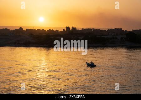 Pêcheurs égyptiens dans un bateau à rames sur le Nil au coucher du soleil. Égypte Banque D'Images