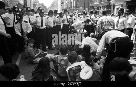 Londres, Royaume-Uni. 9 juin 1984. Affrontement entre la police et des activistes non violents à action directe bloquant les rues menant à Grosvenor Square, Londres, le 9 juin 1984. L'action était en réponse à la visite du président américain Ronald Reagan au Sommet économique mondial de Londres et au déploiement de missiles de croisière américains au Royaume-Uni. La manifestation a coïncidé avec le rassemblement de missiles anti-croisière du CND à Trafalgar Square, à Londres. Grosvenor Square était l'emplacement de l'ambassade américaine au Royaume-Uni au moment de la manifestation. Banque D'Images