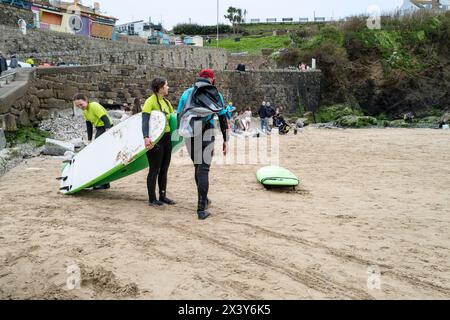 Un moniteur de surf de l'Escape Surf School avec des surfeurs débutants sur la plage de Towan à Newquay en Cornouailles au Royaume-Uni. Banque D'Images