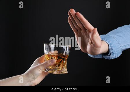 Alcoolisme. Homme refusant le verre de whisky sur fond sombre, gros plan Banque D'Images