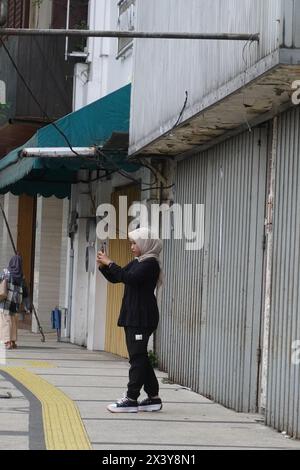 Une femme se tenait debout pour prendre une photo de son amie sur le trottoir près d'un magasin fermé Banque D'Images