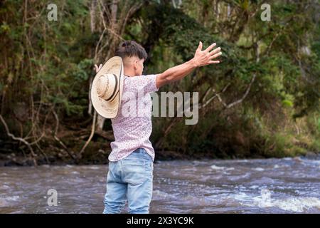 style de vie. jeune homme latin debout dans la rivière, les bras tendus Banque D'Images