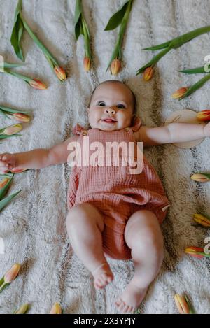 bébé héritière en rose, rayonnant parmi les tulipes printanières Banque D'Images