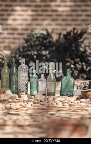 Bouteilles en verre antiques de différentes tailles empilées à côté de pots en terre cuite retournés Banque D'Images