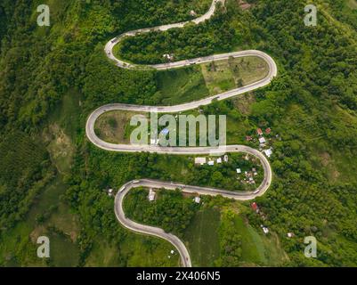 Véhicules roulant sur la route de l'intestin et les collines dans la province de montagne de Bukidnon. Mindanao, Philippines. Banque D'Images