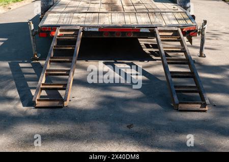 Rampes fixées à un camion pour charger un véhicule ou une machine sur la remorque à plateau lorsqu'elle est stationnée sur l'asphalte de la rue. Banque D'Images