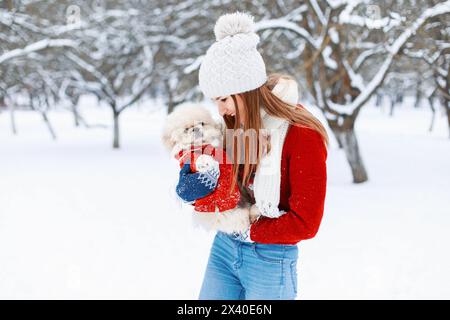 Jeune belle fille dans Un vêtement d'hiver chaud joue avec Un chiot dans ses bras dans le parc. Banque D'Images