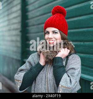 Fille élégante en vêtements tricotés d'hiver vintage sur Un fond d'une vieille maison en bois verte Banque D'Images