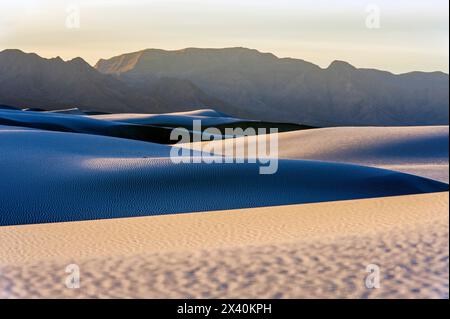 Crête montagneuse silhouette avec la lumière du soleil reflétée sur les dunes de sable créant un paysage sombre dans le parc national de White Sands Banque D'Images