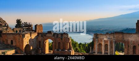 Ruines d'un théâtre grec et vue sur la côte au coucher du soleil à Taormine, Sicile, Italie ; Taormine, Sicile, Italie Banque D'Images