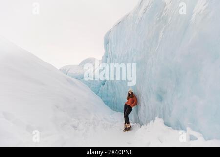 Adolescente appuyée contre des murs de glace sur le glacier Matanuska à Sutton, Alaska ; Sutton, Alaska, États-Unis d'Amérique Banque D'Images