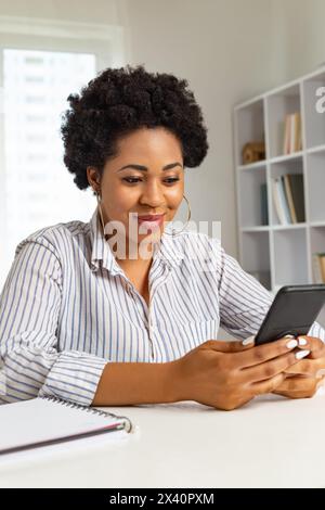 Portrait d'une jeune femme africaine souriante tenant un téléphone. Banque D'Images