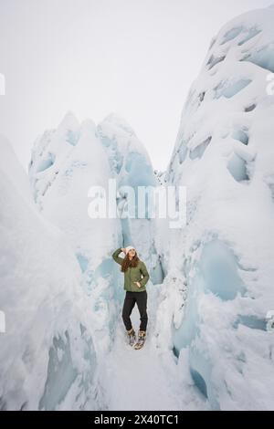 Adolescente appuyée sur le glacier Matanuska au milieu de murs de glace bleus à Sutton, Alaska ; Sutton, Alaska, États-Unis d'Amérique Banque D'Images