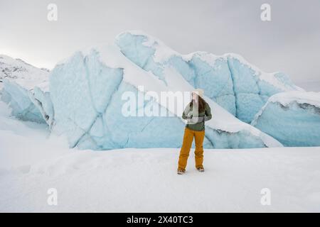 Adolescente debout sur le glacier Matanuska au milieu de murs de glace bleus à Sutton, Alaska ; Sutton, Alaska, États-Unis d'Amérique Banque D'Images