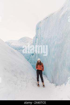 Adolescente debout sur le glacier Matanuska au milieu de murs de glace bleus à Sutton, Alaska ; Sutton, Alaska, États-Unis d'Amérique Banque D'Images