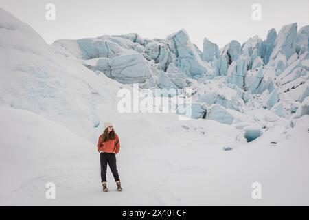 Adolescente debout sur le glacier Matanuska au milieu de murs de glace bleus à Sutton, Alaska ; Sutton, Alaska, États-Unis d'Amérique Banque D'Images