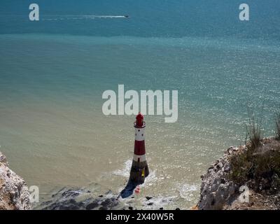 Phare de Beachy Head vu du sentier côtier ci-dessus avec une mer scintillante et un hors-bord par une journée ensoleillée, East Sussex, Royaume-Uni ; East Sussex, Angleterre Banque D'Images