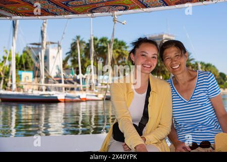 Mère et fille touristes faisant un tour de felouque sur le Nil aux tombes des nobles à Assouan, Egypte ; Assouan, Egypte Banque D'Images