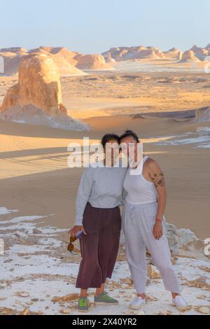 Mère et fille touristes debout dans le désert blanc égyptien avec des formations calcaires au coucher du soleil ; Egypte Banque D'Images