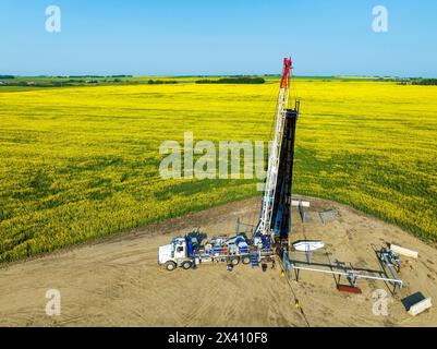 Vue aérienne d'une installation de forage montée sur un camion dans un champ de canola en fleurs, à l'ouest de High River, Alberta ; Alberta, Canada Banque D'Images