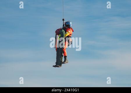 Membre de l'équipage de la Garde côtière américaine suspendu sous un Sikorsky MH-60J Jayhawk effectuant des exercices de formation de sauvetage au parc d'État Cape Disception près de th... Banque D'Images