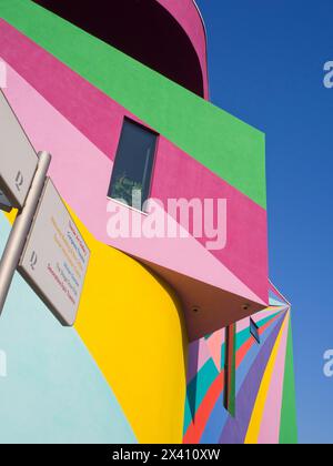 Murs extérieurs sur une galerie d'art peints dans des couleurs vives contre un ciel bleu et un panneau avec une liste de monuments locaux Banque D'Images