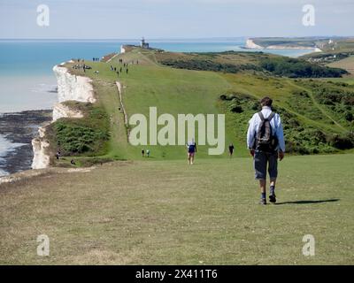 Touristes sur le sentier côtier de Beachy Head avec le phare de belle tout et la falaise de Seven Sisters en arrière-plan, Beachy Head, East Sussex, Royaume-Uni Banque D'Images
