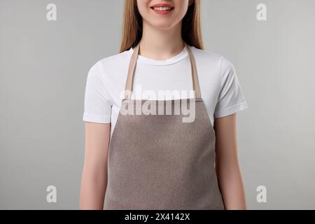 Femme portant tablier de cuisine sur fond gris, gros plan. Maquette pour le design Banque D'Images