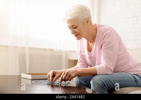 Femme assise à table jouant avec Puzzle Banque D'Images