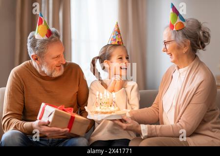 Grands-parents célébrant l'anniversaire de leurs petites-filles dans un salon confortable Banque D'Images