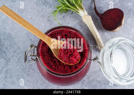 Sauce crémeuse au raifort de betterave en pot avec une cuillère en bois sur le dessus sur un fond gris. Apéritif ou condiment pour viande et poisson. Nourriture végétalienne saine. à Banque D'Images